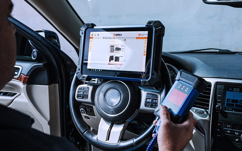 Mecânico usa tablet com a plataforma Doutor-IE para fazer testes dentro da cabine do veículo.